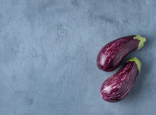 Twee sappige graffiti van aubergines liggen op een blauwe betonnen tafelblad kopie kopie sace aan de linkerkant dorp