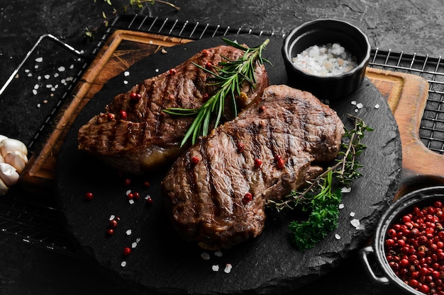 Twee sappige rib eye steak kruiden en specerijen op een zwarte stenen achtergrond