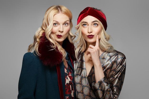 Twee sceptische mannequins in retro-jurk en jas. Schoon fris gezicht van mooi meisje met natuurlijke make-up.