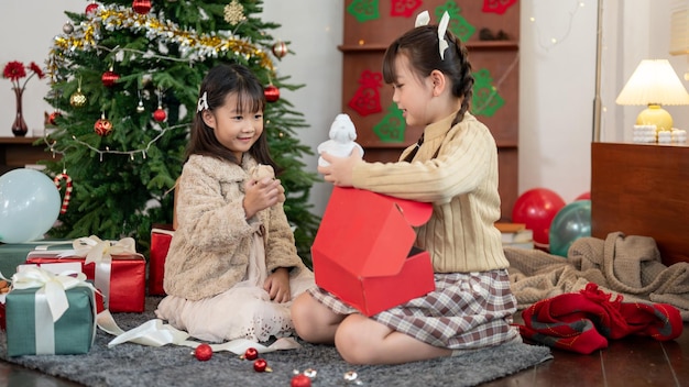 Twee schattige jonge Aziatische meisjes genieten ervan om samen hun kerstcadeau thuis te openen