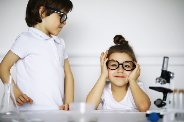 Twee schattige kinderen bij scheikundeles die experimenten maken die op witte achtergrond worden geïsoleerd