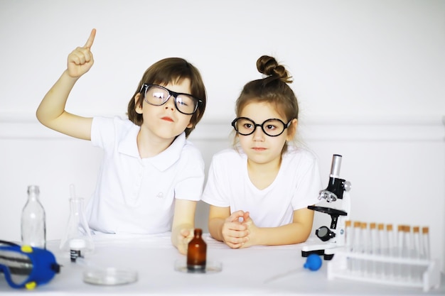 Twee schattige kinderen bij scheikundeles die experimenten maken die op witte achtergrond worden geïsoleerd