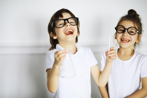 Twee schattige kinderen bij scheikundeles die experimenten maken die op witte achtergrond worden geïsoleerd