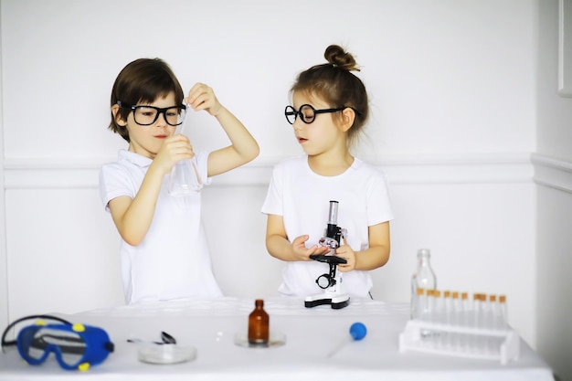 Twee schattige kinderen bij scheikundeles die experimenten maken op witte achtergrond
