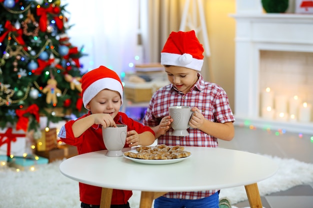 Twee schattige kleine broers die koekjes eten op de achtergrond van de kerstversiering