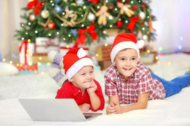 Twee schattige kleine broers die laptop gebruiken op het oppervlak van de kerstversiering