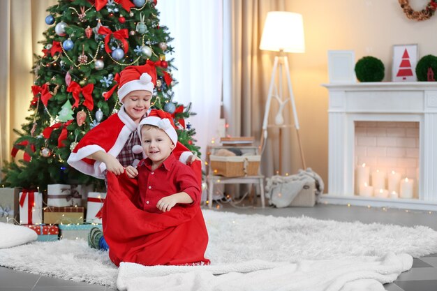 Twee schattige kleine broers spelen met Santa tas op kerstversiering achtergrond