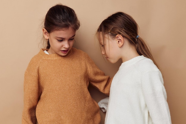 Twee schattige kleine meisjes knuffelen vriendschap levensstijl beige achtergrond