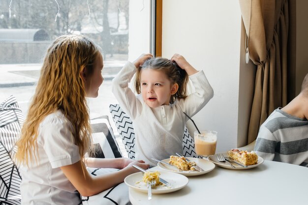 Twee schattige kleine meisjes zitten in een café en spelen op een zonnige dag. recreatie en levensstijl.