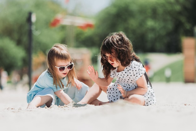 Twee schattige meisjes die in de zomer op het strand spelen