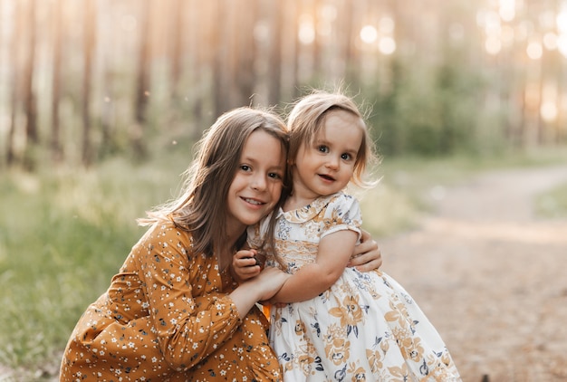 Twee schattige meisjeszusters spelen in de zomer in het park. Familie tijd.