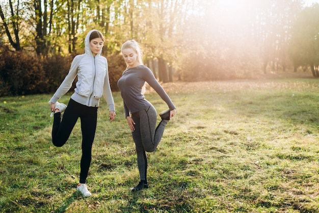 Twee schattige vriendinnen strekken zich uit voordat ze buiten trainen.