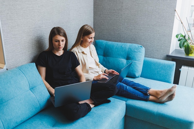 Twee schattige vrouwen chatten met hun vrienden via een videogesprek met behulp van een laptop in de woonkamer Vrienden vriendschapstijd samen Vriendinnen zitten op de bank en kijken naar een film