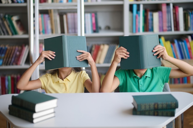 Twee schoolkinderen die plezier hebben in de bibliotheek