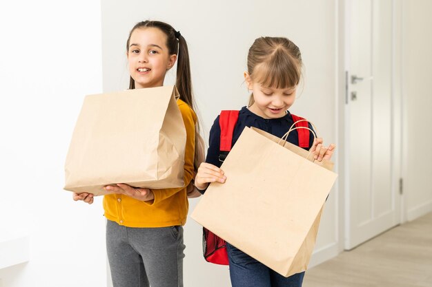 twee schoolmeisjes met bezorgpakketten.