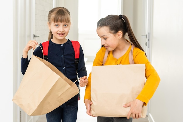 twee schoolmeisjes met bezorgpakketten.