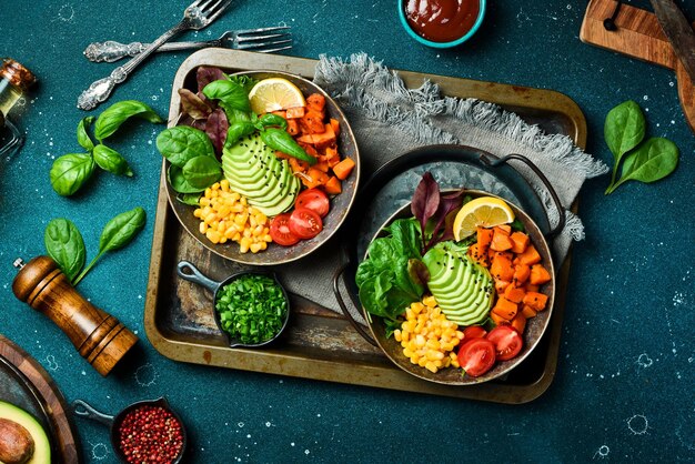 Foto twee schotels met pompoen avocado kersen tomaten groene salade en maïs op een metalen dienblad gezond evenwichtig eten