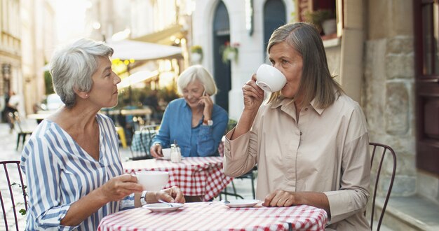 Twee senior vriendinnen zitten op het terras