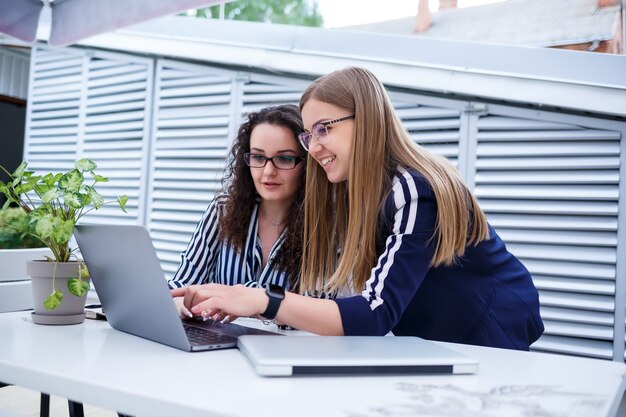 Twee serieuze zakenvrouwenmeisjes bespreken een zakelijk project, werken samen op kantoor, serieuze vrouwelijke consultant en klant praten tijdens een vergadering, gerichte uitvoerende collega's delen ideeën