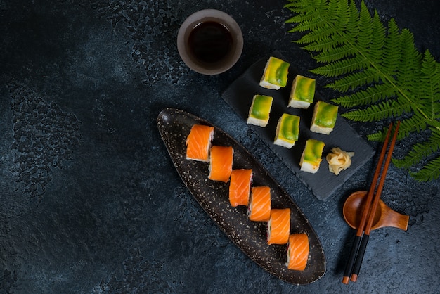 Twee sets sushi rolt met groenten en zeevruchten liggen op een zwarte achtergrond. Bovenaanzicht
