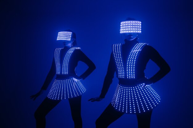 Twee sexy discodanseressen bewegen zich in UV-kostuums