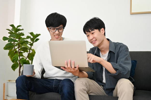 Twee slimme jonge Aziatische mannelijke studenten doen samen een project in de woonkamer