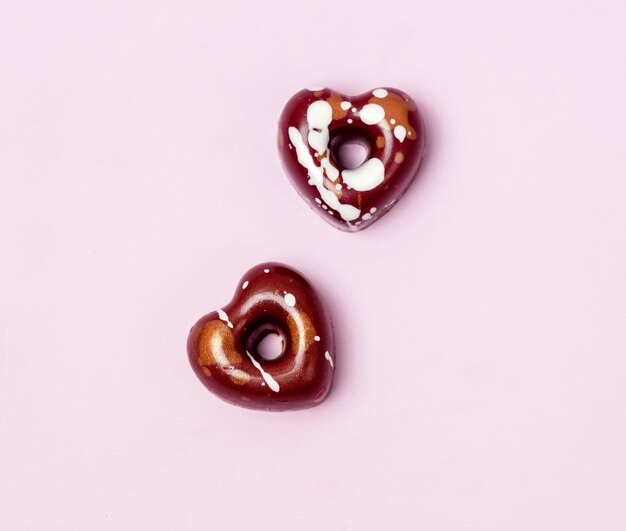 Twee smakelijke luxe bonbons in de vorm van harten Chocoladesuikergoed op roze achtergrond Snoepjes voor Valentijnsdag Bovenaanzicht Minimal