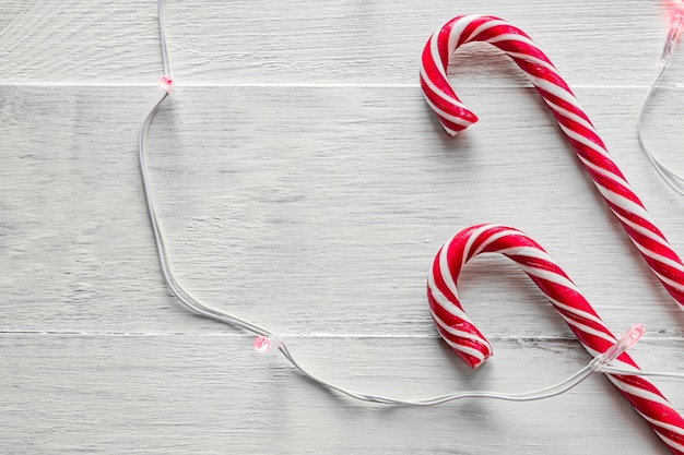 Twee snoep stokken en elektrische slinger op houten achtergrond. traditioneel kerstsuikergoed.