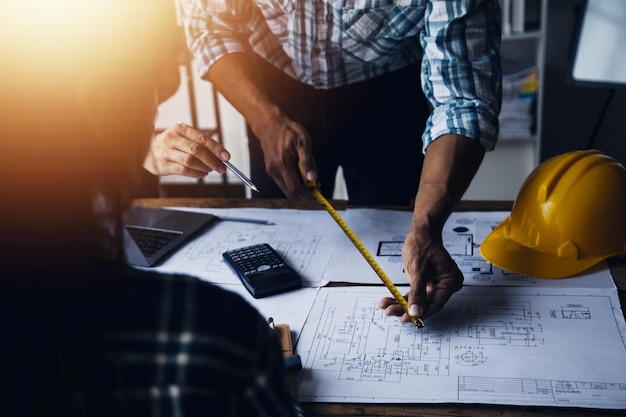 Twee specialisten inspecteren commercieel industrieel gebouw bouwplaats onroerend goed project met civiel ingenieur investeerder gebruik laptop op de achtergrond kraan wolkenkrabber betonnen bekisting frames