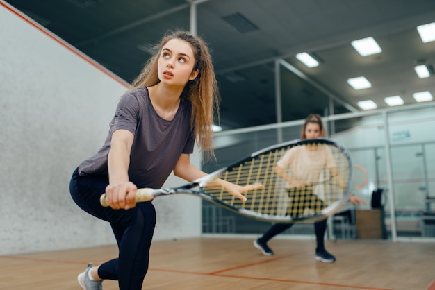 Twee spelers met squashracket die op de baan spelen