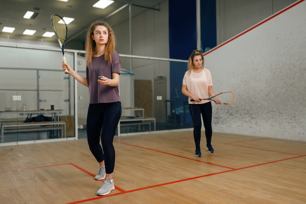 Twee spelers met squashracket die op de baan spelen