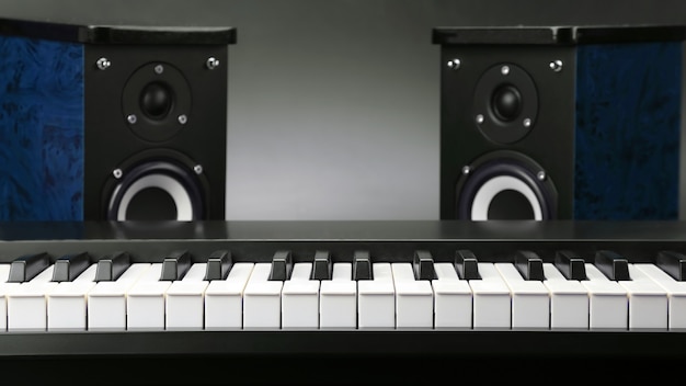 Twee stereo luidsprekers en pianotoetsen close-up op donkere achtergrond. items voor opname