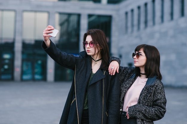 Twee stijlvolle meisjes nemen een selfie