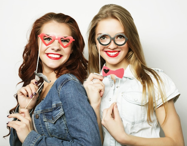 Twee stijlvolle sexy hipster meisjes beste vrienden klaar voor een feestje op een grijze achtergrond