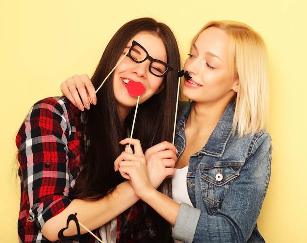 Twee stijlvolle sexy hipster meisjes beste vrienden klaar voor feest op gele achtergrond