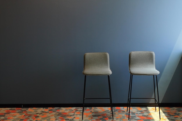 Twee stoelen in het interieur van een lege blauwe kamer. Licht uit het raam aan de rechterkant.