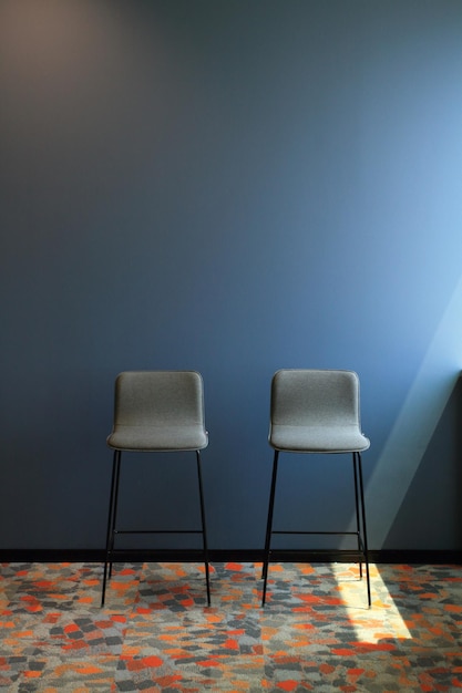 Twee stoelen in het interieur van een lege blauwe kamer. Licht uit het raam aan de rechterkant.