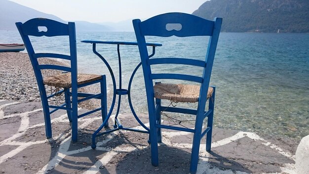 Foto twee stoelen met tafel aan de oever van het meer