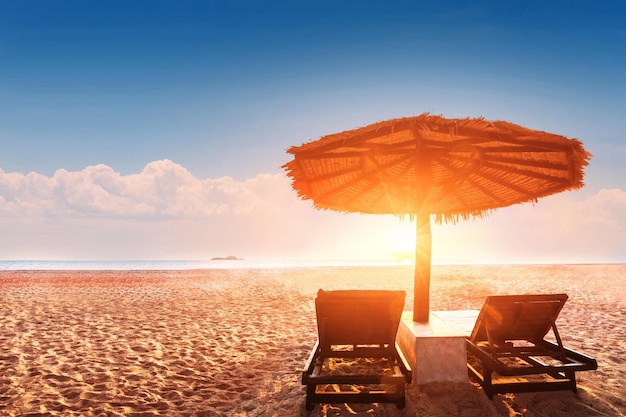 Twee stoelen onder een parasol op een strand