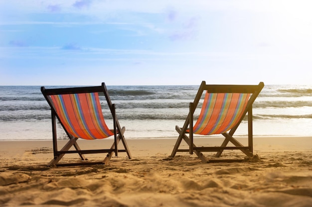 Twee strandstoelen op een strand met daarachter de ondergaande zon