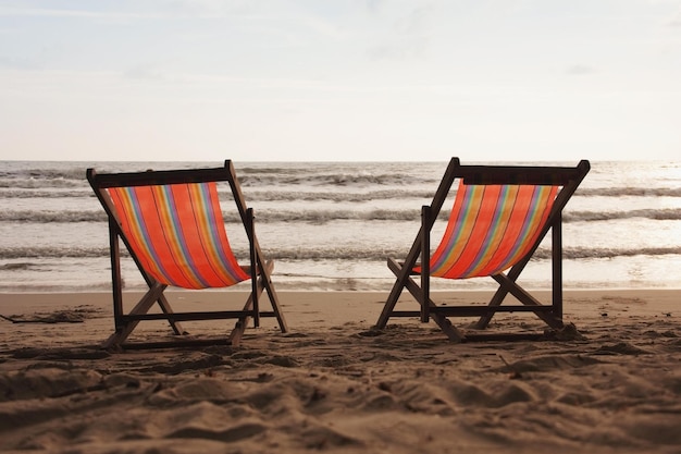 Twee strandstoelen op het strand met daarachter de ondergaande zon.