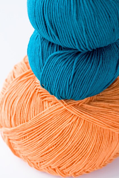 Twee strengen garen en een turquoise oranje garen en twee breinaalden