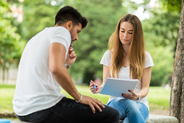 Twee studenten die samen studeren zittend op een bank openlucht