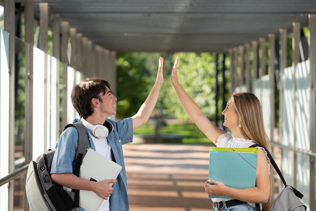 Twee studenten high-five elkaar in een gang