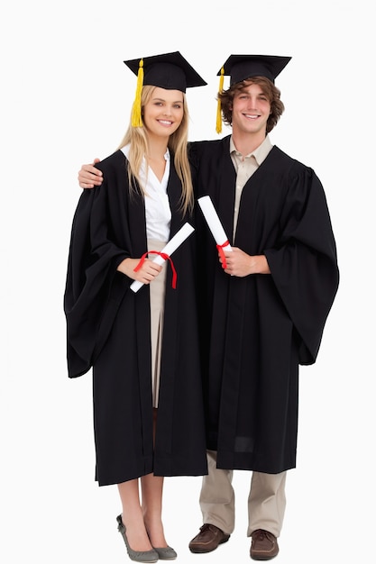 Twee studenten in graduate gewaad schouder aan schouder