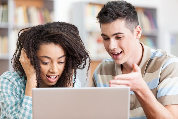 Twee studenten werken aan een laptop in een bibliotheek