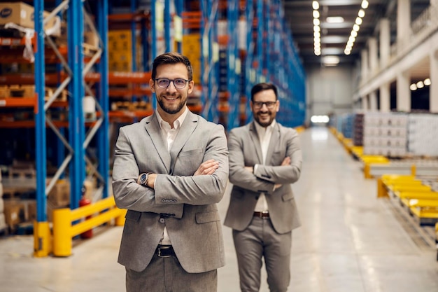 Foto twee succesvolle managers staan met gekruiste armen in het magazijn