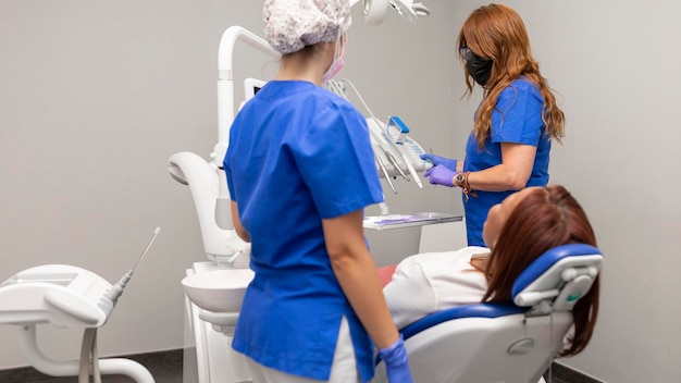 Twee tandartsvrouwen die de hulpmiddelen voorbereiden één van haar cliënten bij de tandkliniek