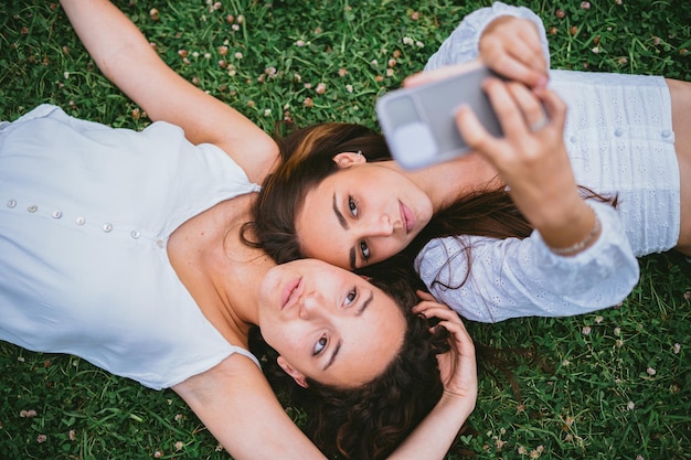 Twee tienermeisjes plaatsen een foto op sociale media ze liggen op het gras in een park