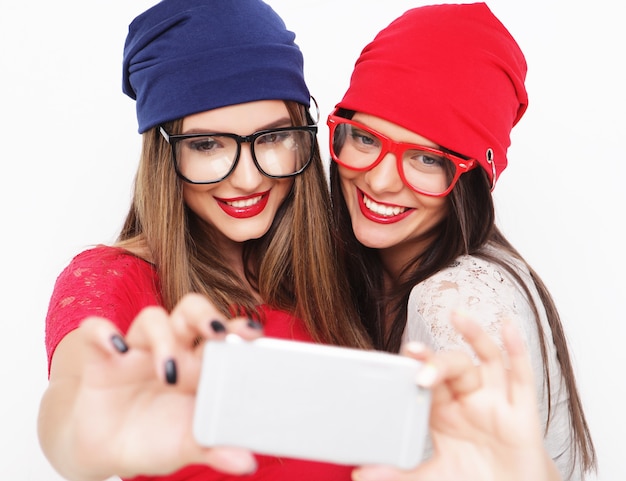 Twee tienermeisjes vrienden in hipster outfit maken selfie op een telefoon.